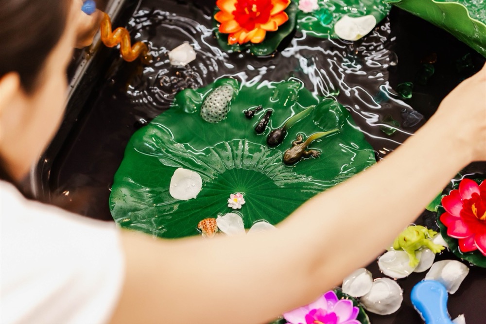 水の中に沈んだ小さな貝や生きもののおもちゃに、手をのばしている