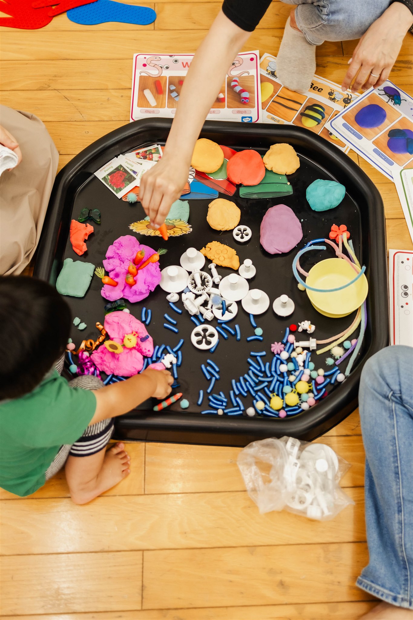 色とりどりの素材が入ったトレイに、子どもたちが手をのばしている